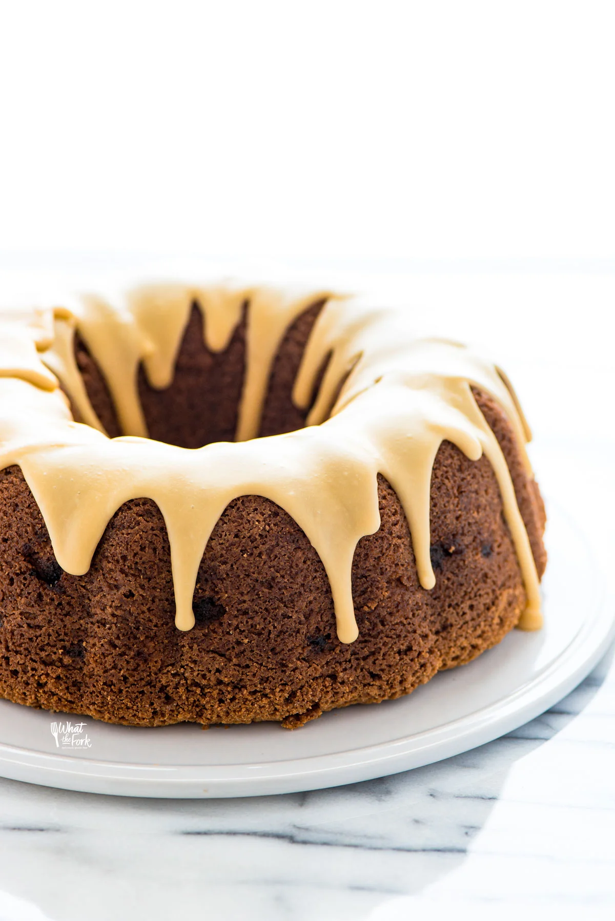 Gluten Free Apple Cake topped with maple glaze on a flat white cake plate ready to serve.