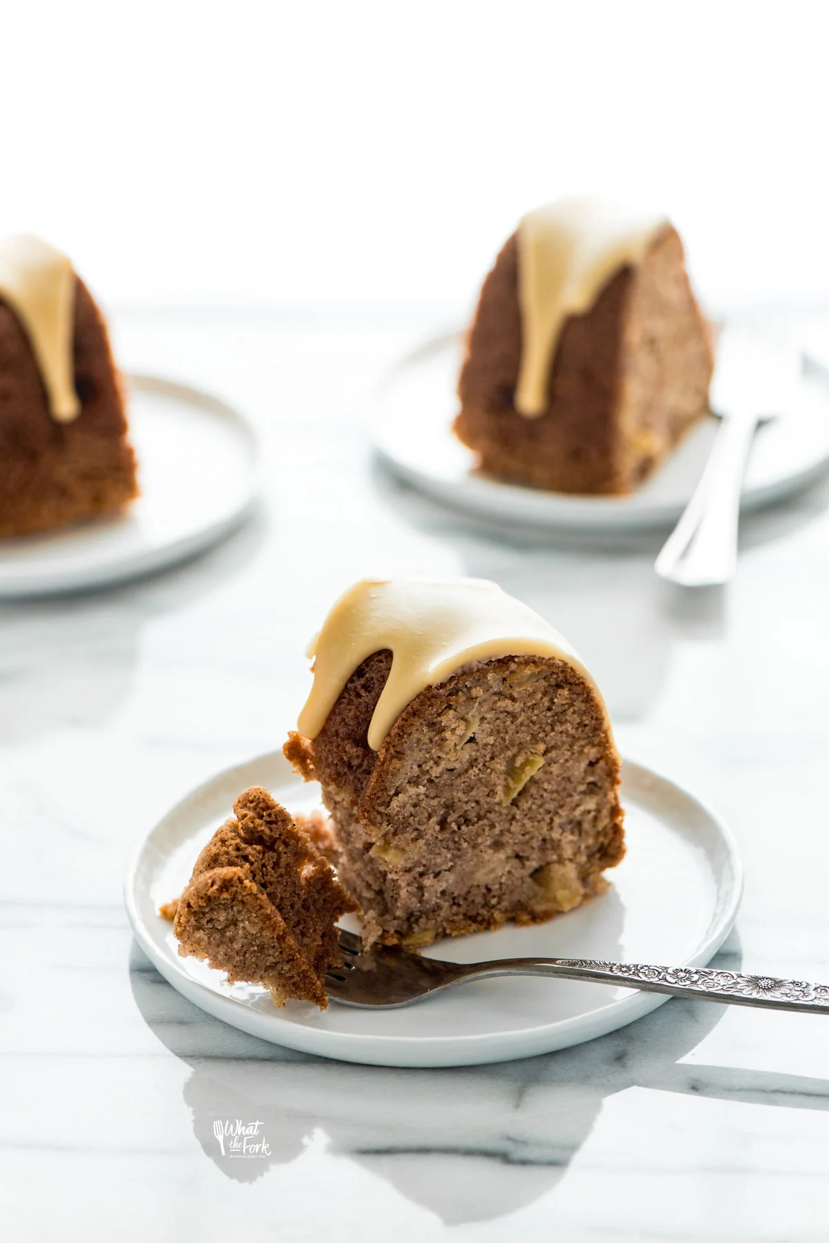 a slice of gluten free apple cake on a small white plate with a forkful removed that's resting on the plate