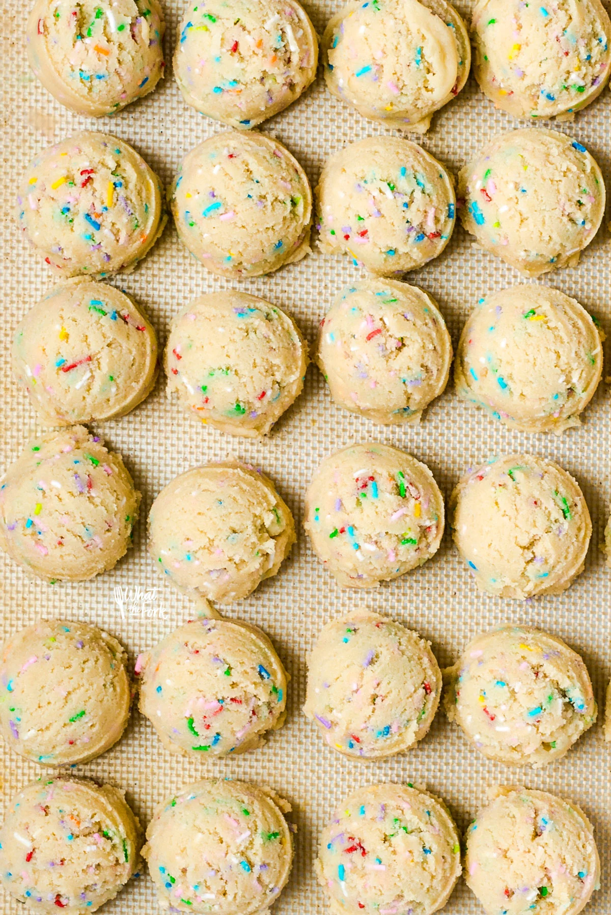gluten free sugar cookie dough with sprinkles scooped into mounds on natural colored parchment paper
