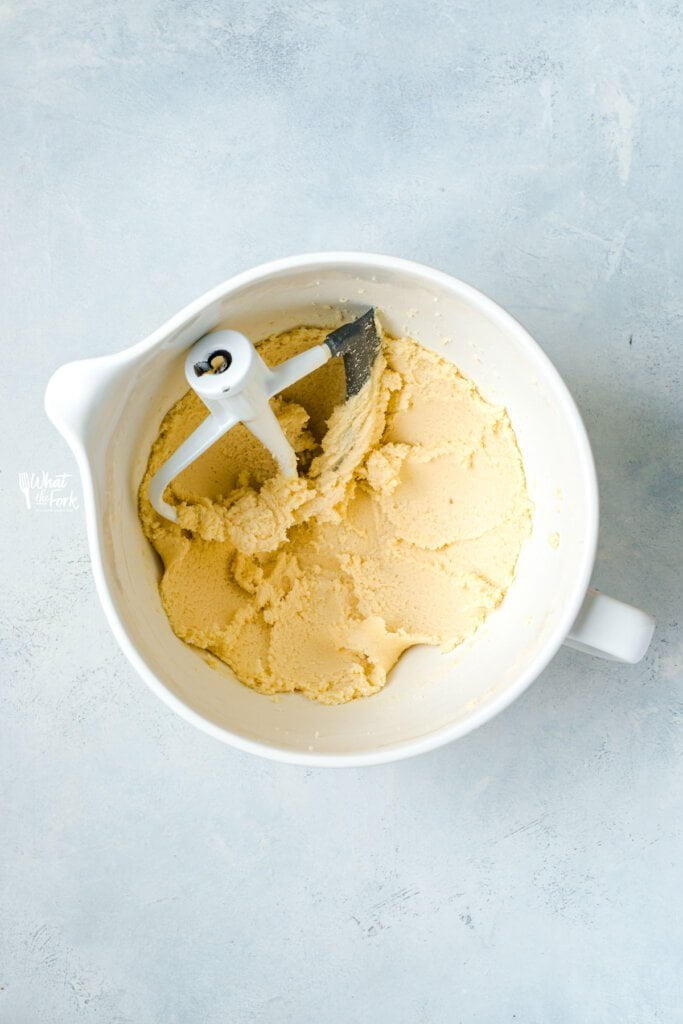 butter and sugar creamed together in a white stand mixer bowl with the paddle attachment.