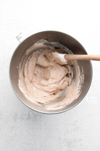 Nutella Whipped Cream in a large silver bowl with a white rubber and wood spatula ready to be used as a filling for Nutella Pavlovas
