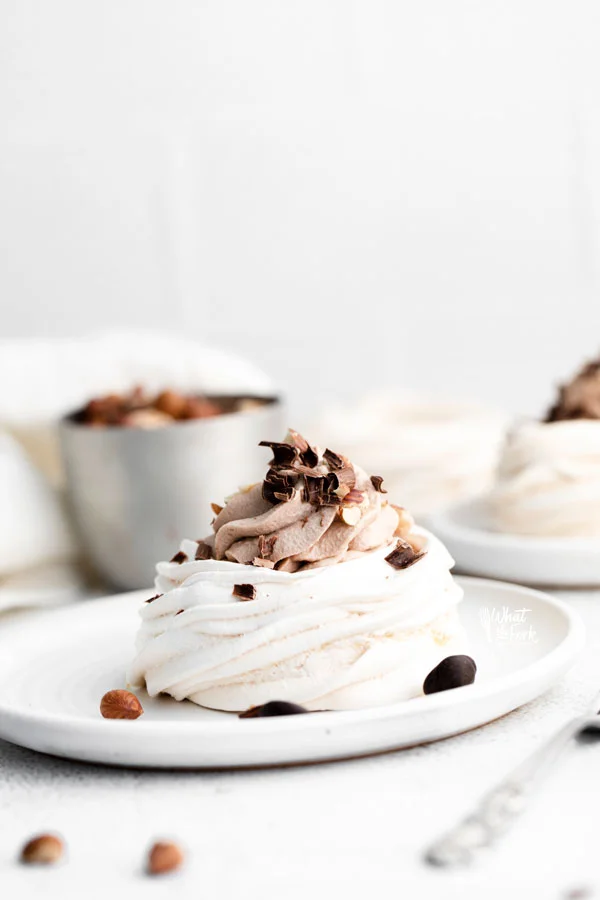 Nutella Pavlovas filled with Nutella Whipped Cream on round white plates