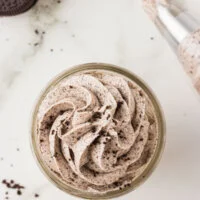 Cookies and Cream frosting piped into a small glass jar and topped with a few crushed gluten free Oreo crumbs