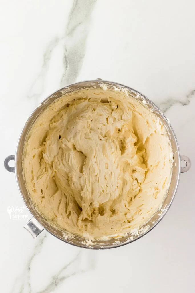 Vanilla buttercream frosting in a large silver bowl ready for Oreo cookie crumbs to be added to make Cookies and Cream frosting