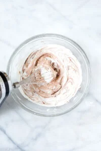 Nutella and whipped cream starting to mix together with an electric hand mixer fitted with a whisk attachment