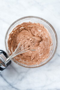 Nutella whipped cream in a bowl with an electric hand mixer with a whisk attachment