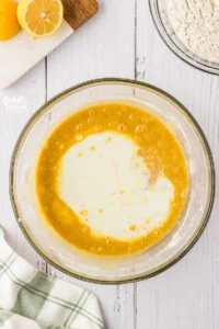 milk and lemon juice added to gluten free cake batter in a large glass bowl