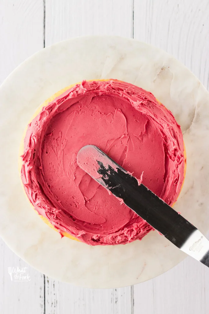 blackberry buttercream frosting being spread on a layer of cake