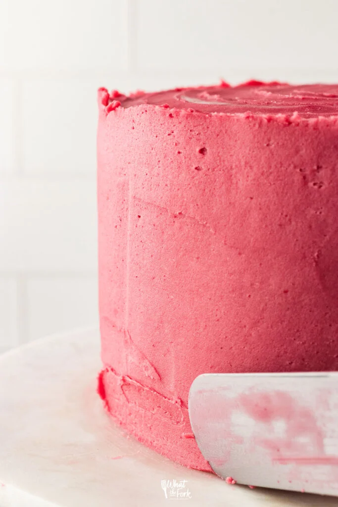 blackberry frosting being smoothed out on a cake to decorate