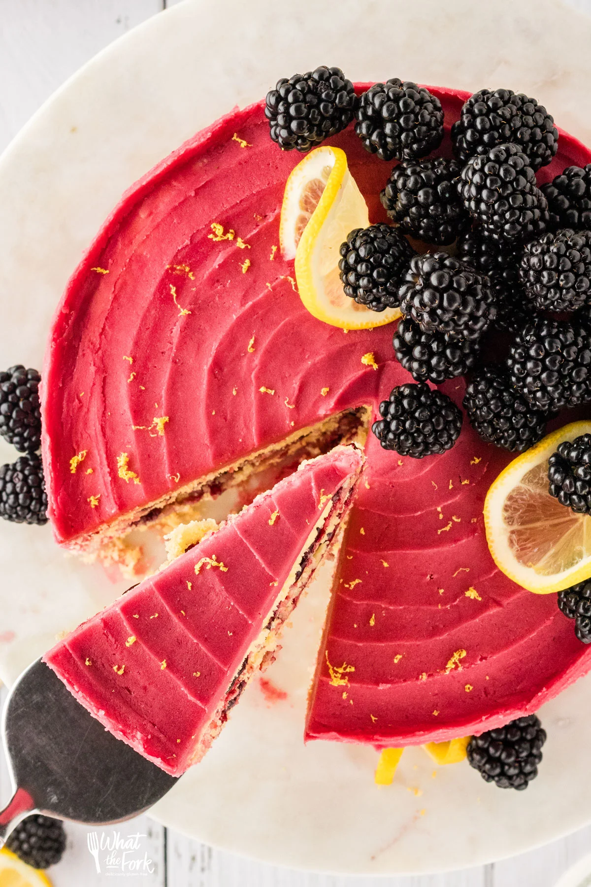a slice of gluten free lemon blackberry cake sliced and being removed with a cake server