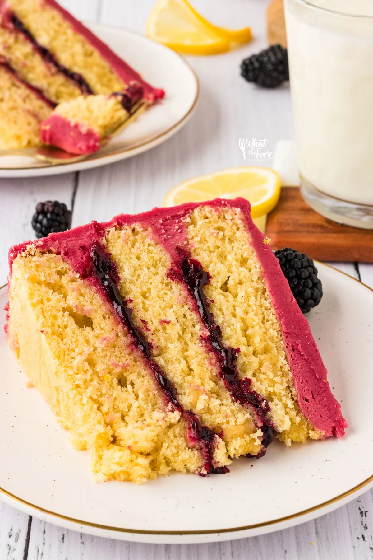 a slice of Gluten Free Lemon Blackberry Cake  on a stack of round white plates