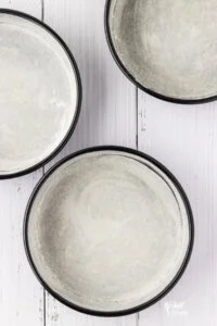 overhead shot of three round cake pans that have been greased and coated in flour.