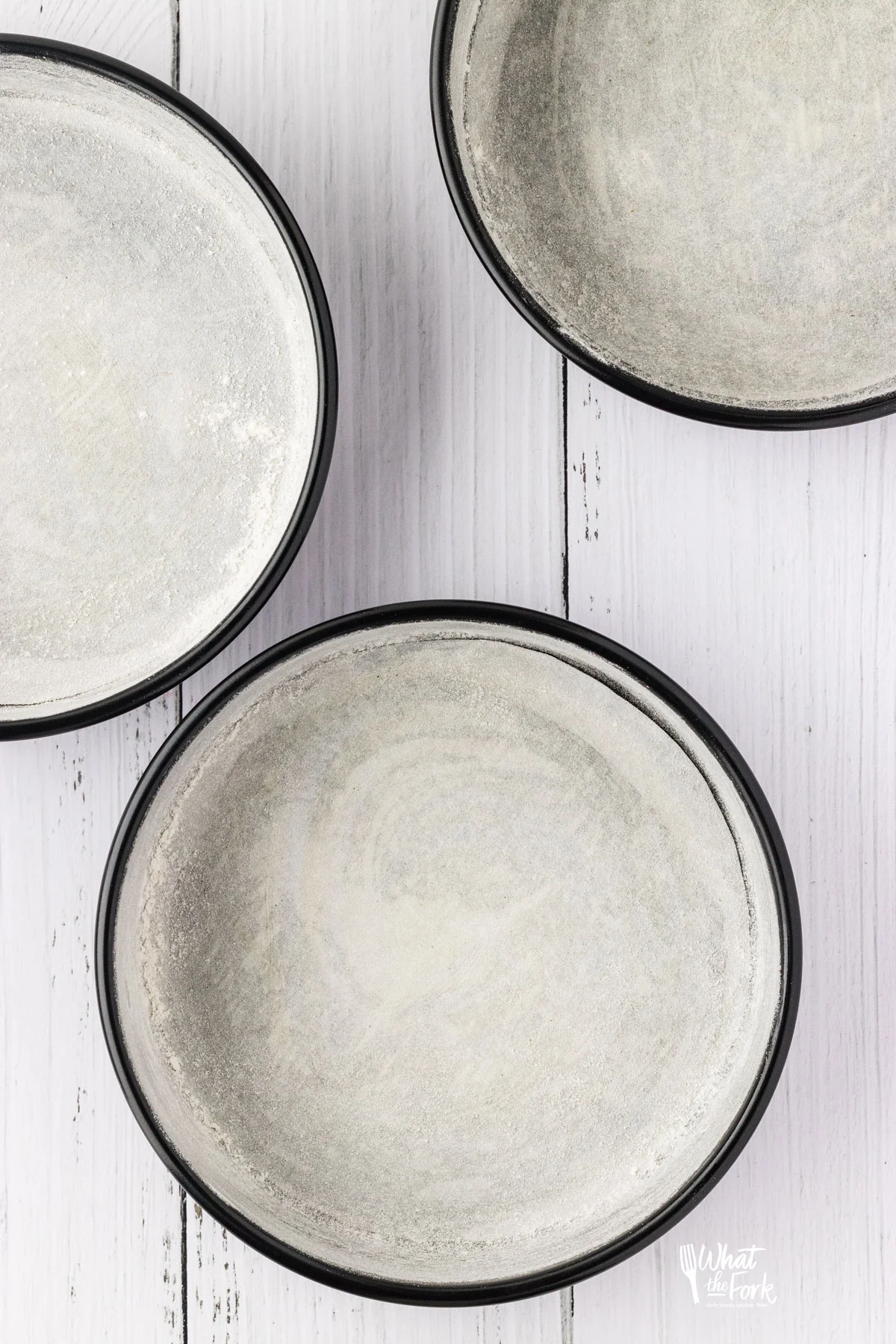 overhead shot of three round cake pans that have been greased and coated in flour.