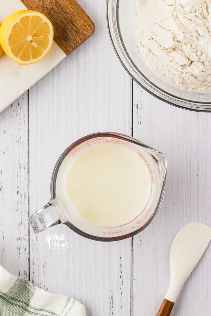 overhead shot of lemon juice and milk in a glass liquid measuring cup