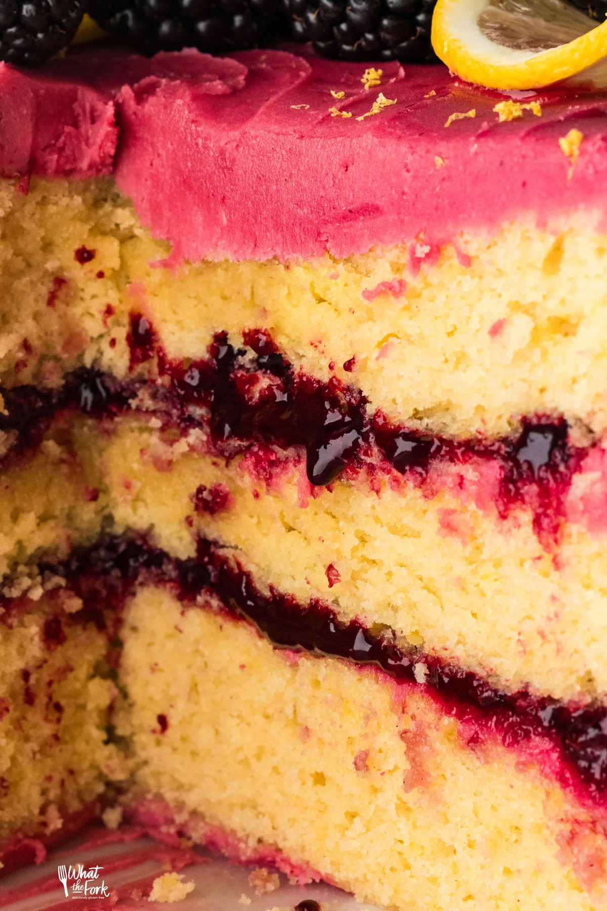 close up shot of a 3 layer lemon cake filled with blackberry cake filling and frosted with blackberry buttercream