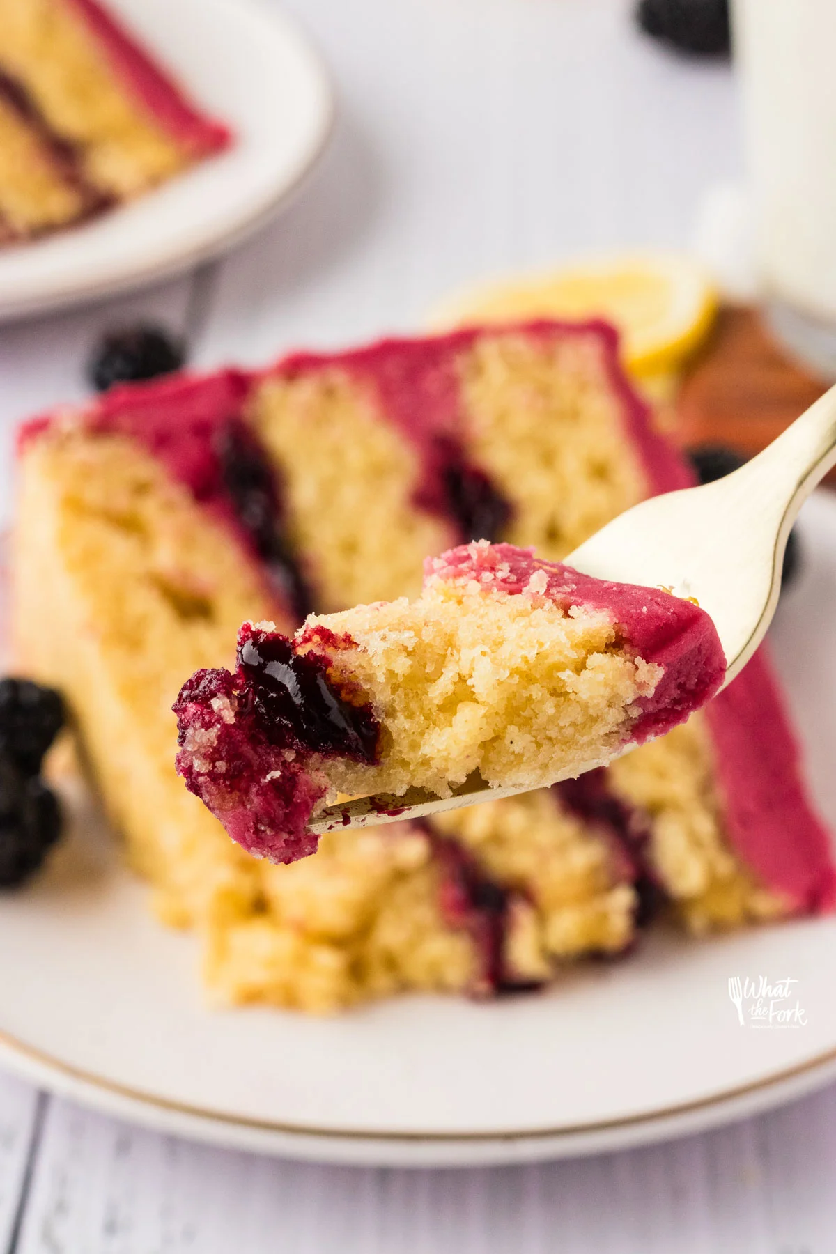 a forkful of lemon cake with blackberry cake filling.