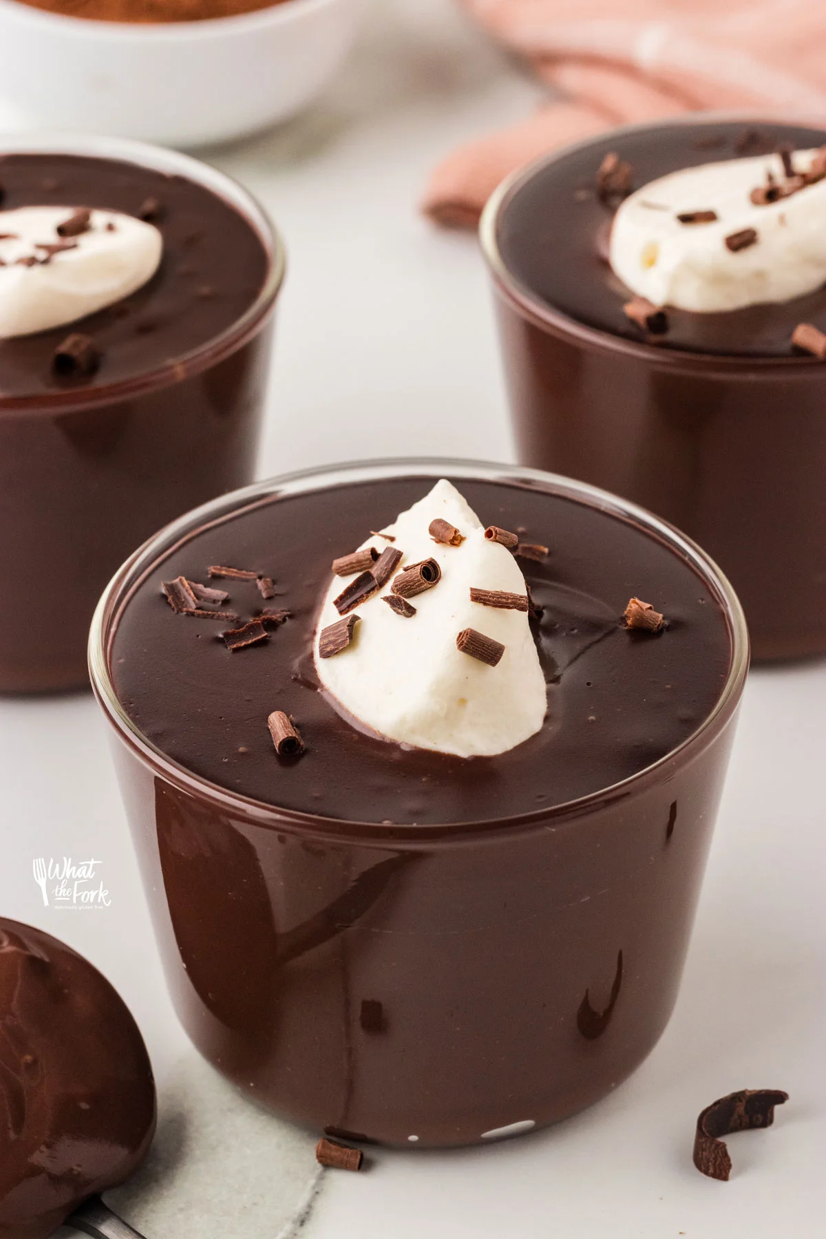 a cooked Gluten Free Chocolate Pudding Recipe in small clear glass cups topped with whipped cream and chocolate shavings