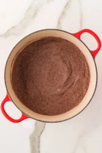 dry ingredients whisked together in a white and red Dutch oven to make gluten free chocolate pudding