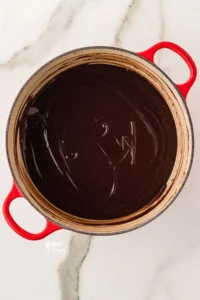 cooked gluten free chocolate pudding in a white and red Dutch oven