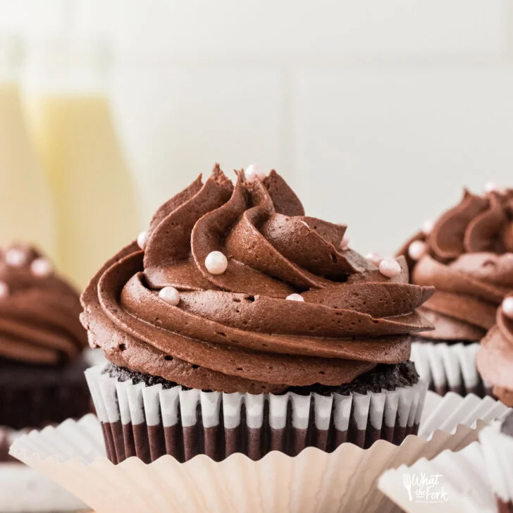 baked Moist and Rich Gluten Free Chocolate Cupcakes in white paper liners frosted with chocolate frosting and decorated with small pearl sprinkles