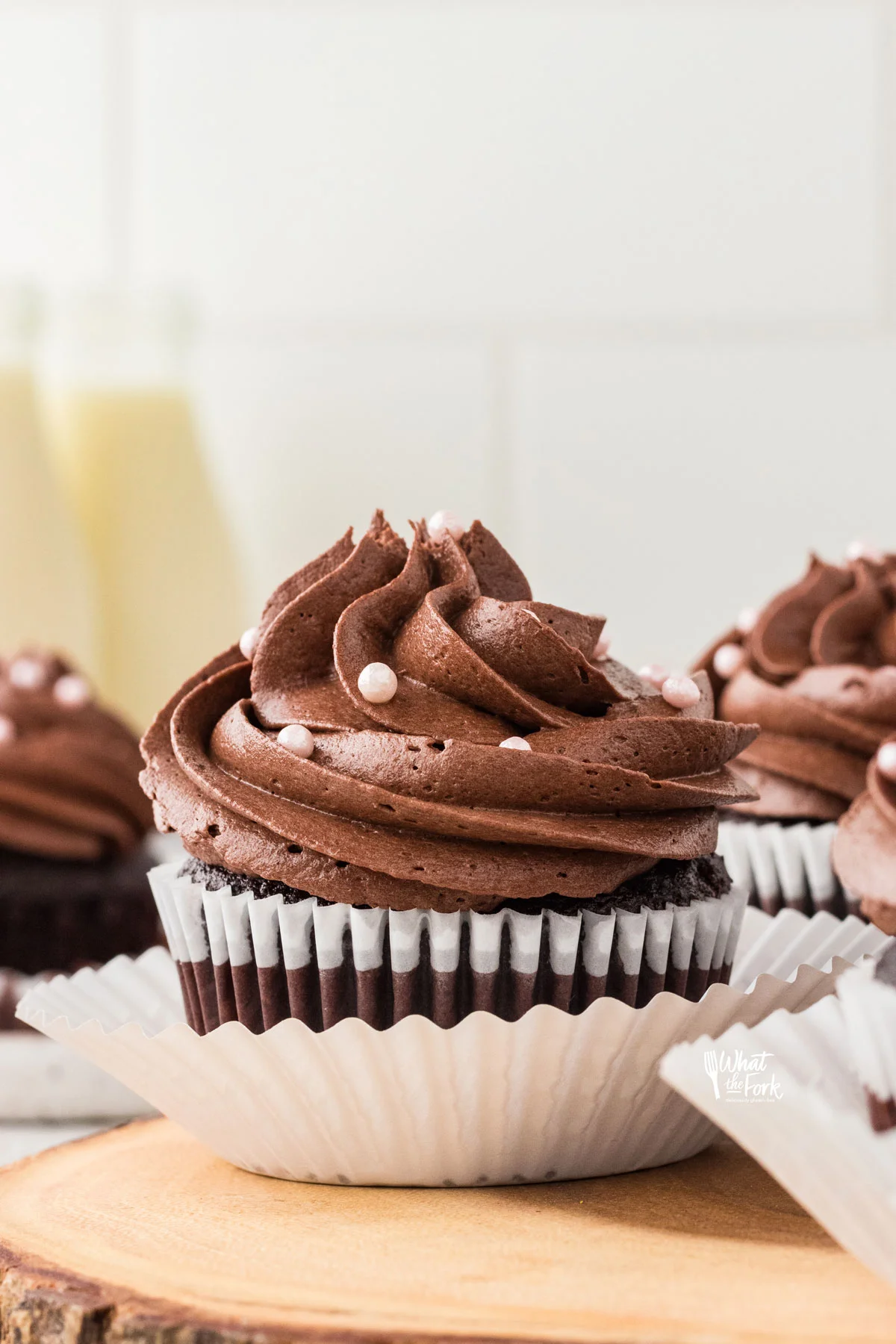 baked Moist and Rich Gluten Free Chocolate Cupcakes in white paper liners frosted with chocolate frosting and decorated with small pearl sprinkles