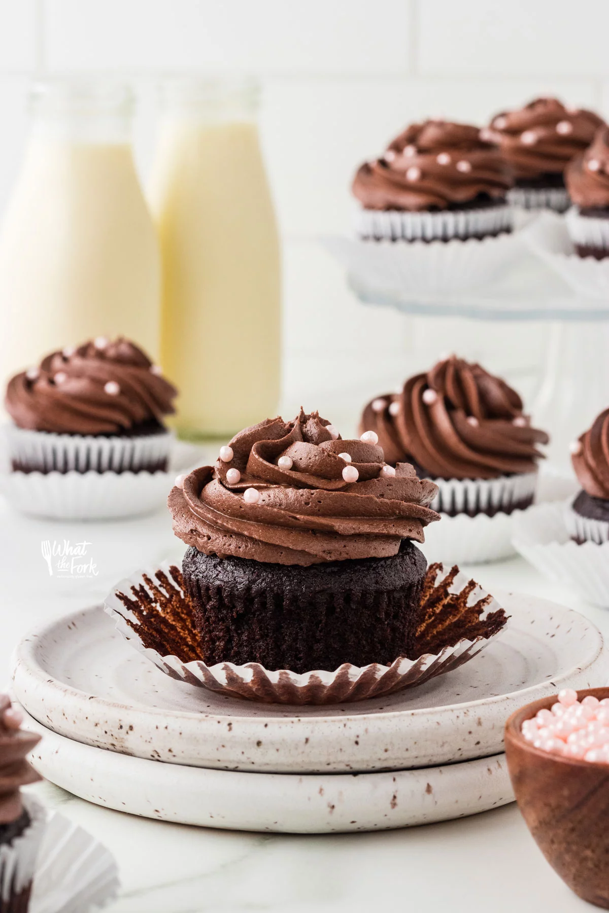 baked Moist and Rich Gluten Free Chocolate Cupcakes with chocolate buttercream frosting on small white plates ready to be eaten.