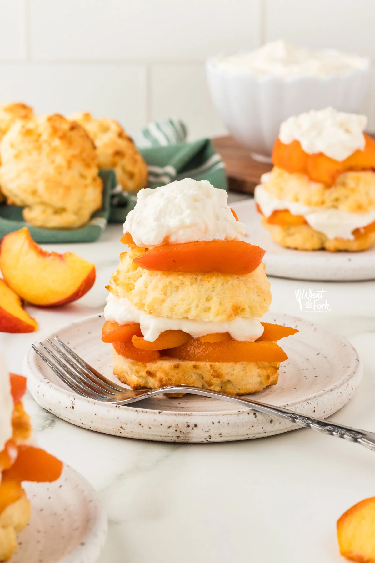 a Gluten Free Peach Shortcake made with Biscuits plated on a small round white plate with a silver fork