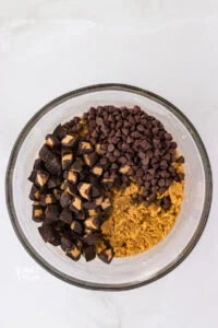 chocolate chips and chopped peanut butter cups added to gluten free peanut butter cookie dough ready to be mixed in