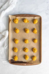 unbaked pumpkin cookie dough on a parchment paper lined baking sheet