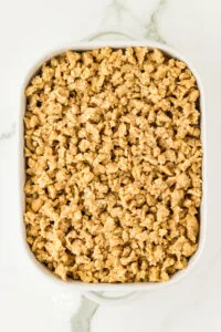 gluten free crisp topping covers the apples in a white 9x13 baking dish