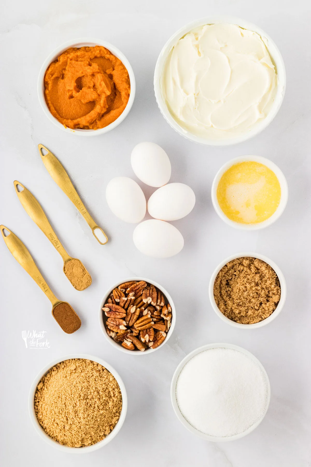 overhead shot of ingredients in individual bowls and measuring spoons to make Layered Pumpkin Cheesecake with a Gluten Free Crust