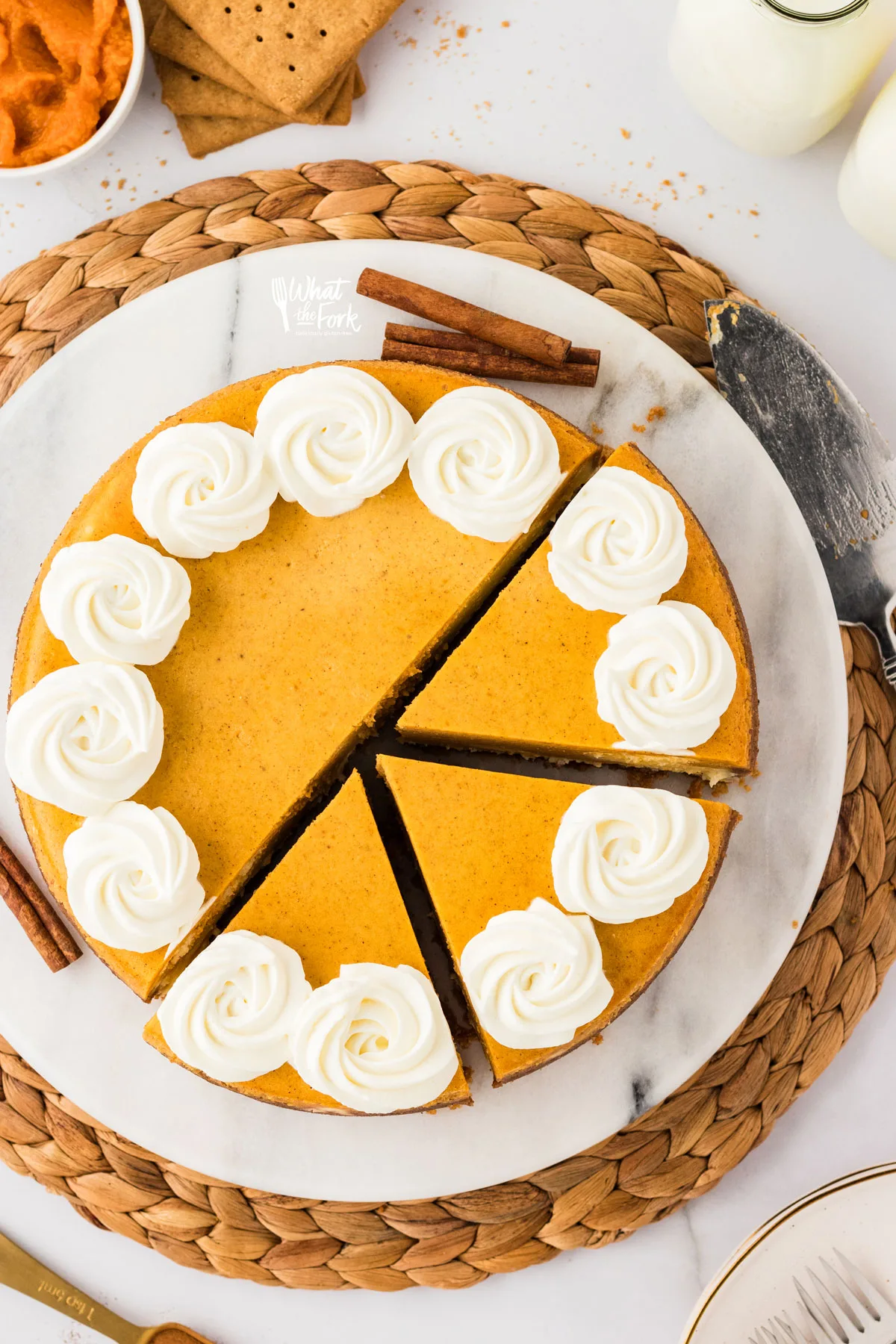 overhead shot of a baked and sliced Layered Pumpkin Cheesecake with a Gluten Free Crust with a whipped cream piped border