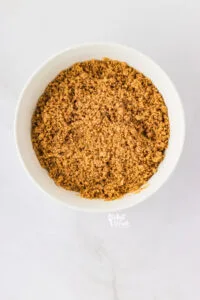 ground pecans, ground graham crackers, and melted butter mixed together in a white bowl