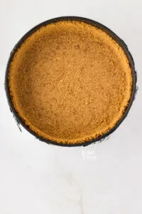 gluten free graham cracker crust with pecans pressed into the bottom and up the sides of a black springform pan