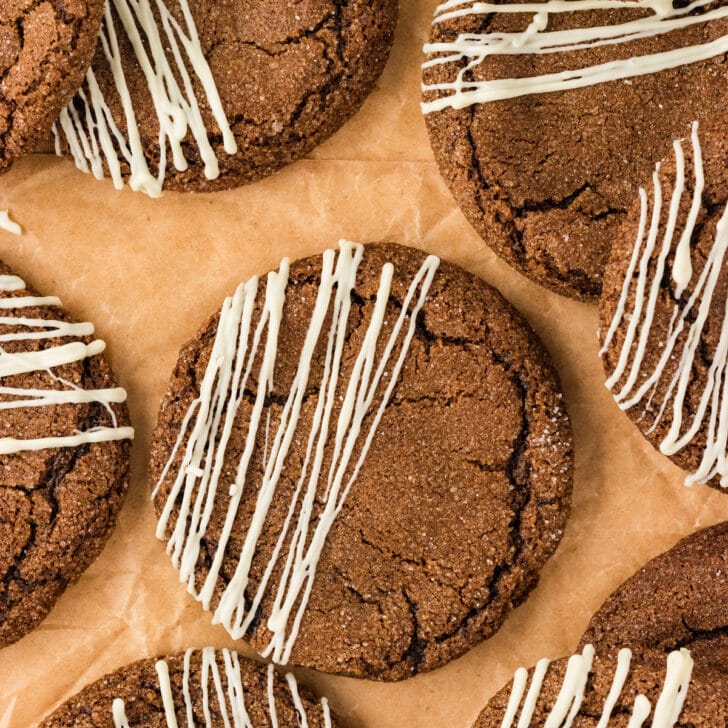 overhead shot of baked Double Molasses Gluten Free Ginger Cookies that have been drizzled with white chocolate on top of brown parchment paper