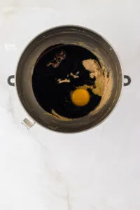 molasses and egg added to beaten butter and sugar in a silver stand mixer bowl