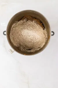 dry ingredients added to the wet ingredients in a silver stand mixer bowl to make gluten free ginger molasses cookies