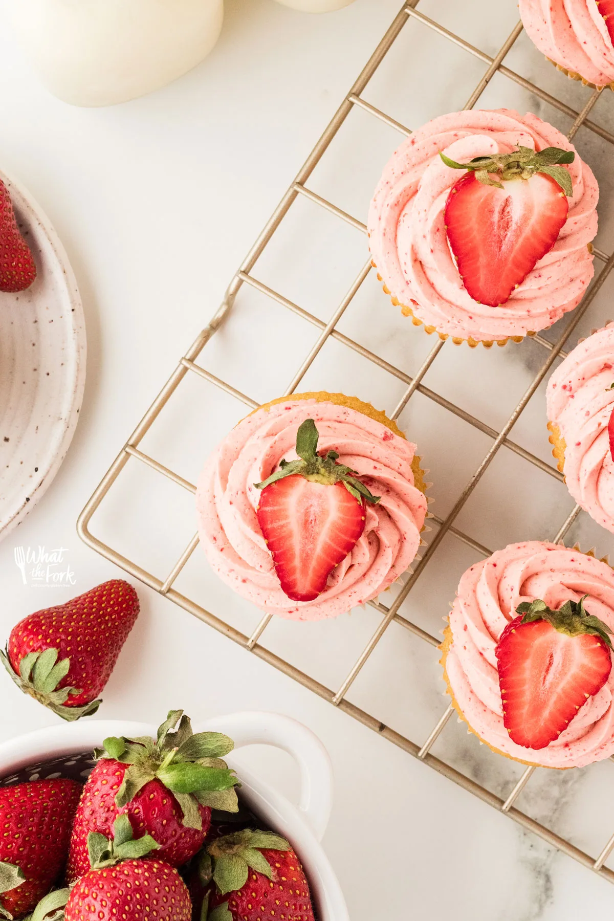 Naturally Flavored Strawberry Frosting Recipe piped onto cupcakes and topped with a halved strawberry