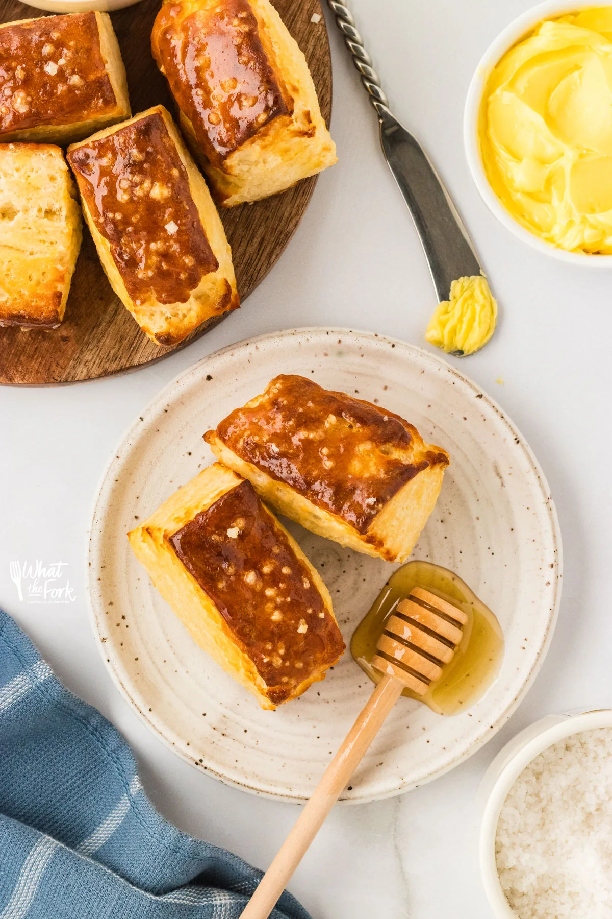two Prezel Biscuits on a small round white plate with a honey ladle