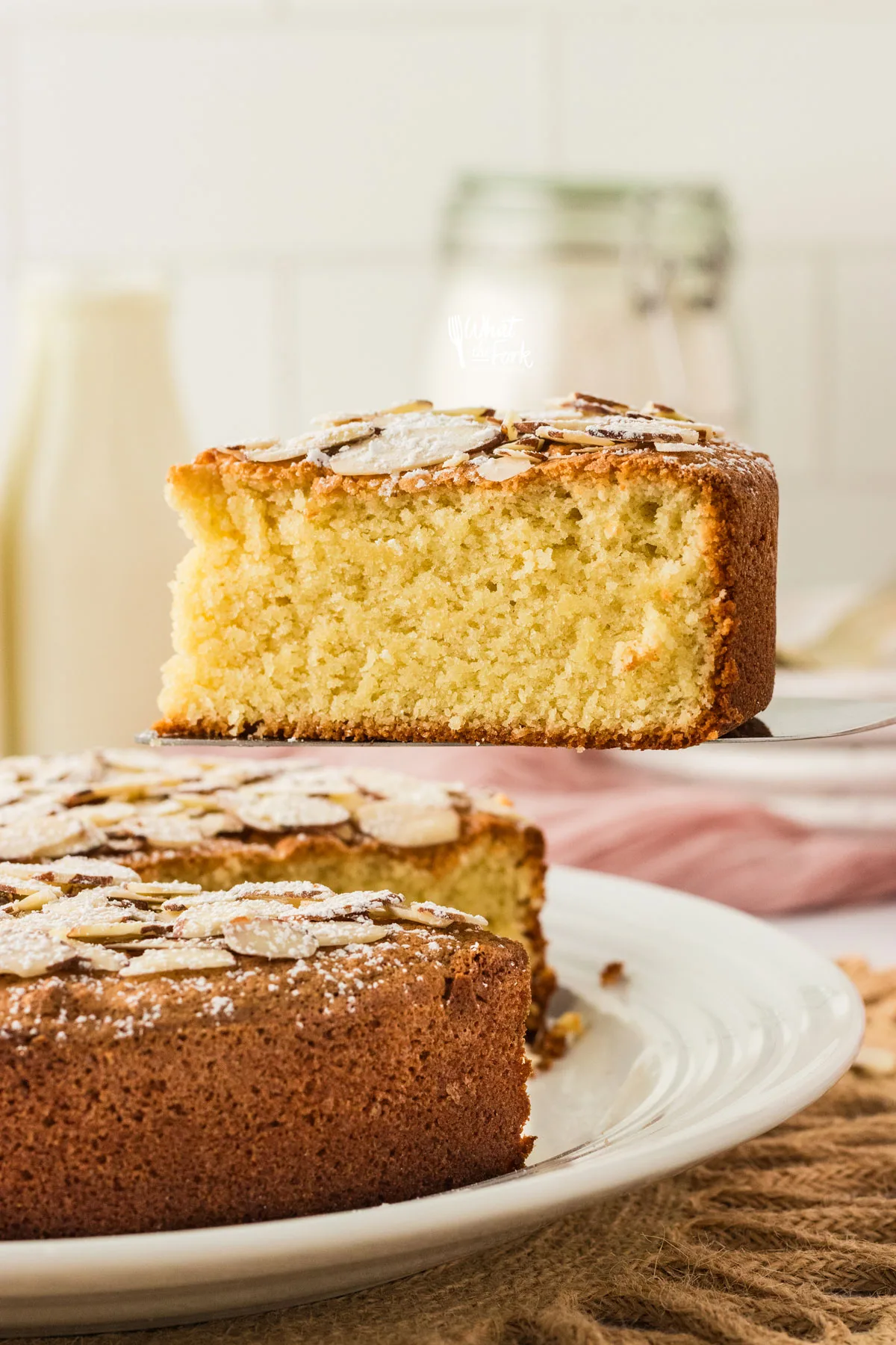 a slice of almond flour cake that has been sliced and is held in the air with a cake server