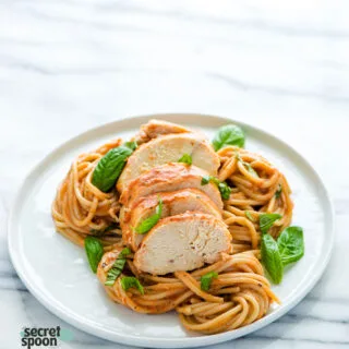 Slow Cooker Creamy Tomato Basil Chicken sliced and served over saucy spaghetti and topped with fresh basil