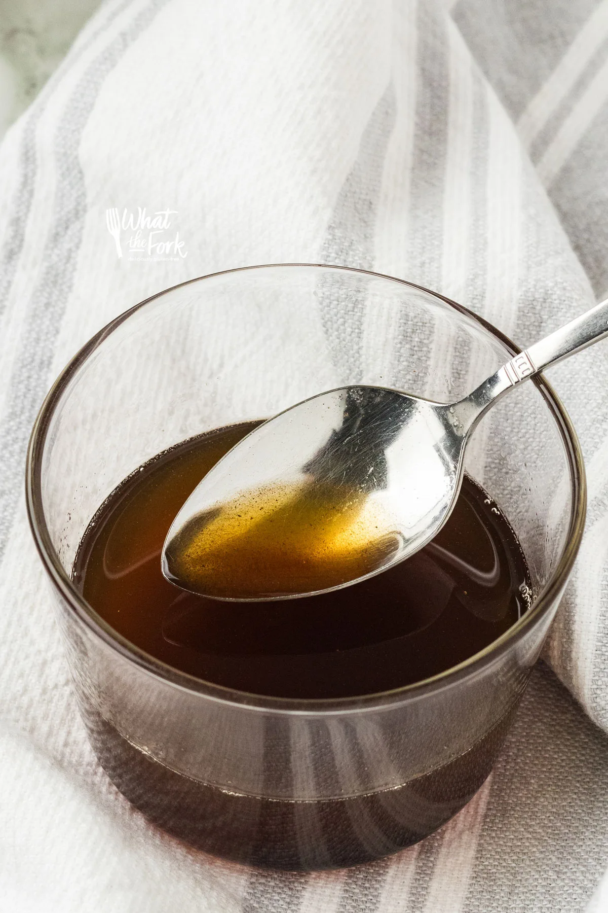 brown butter in a small glass bowl with a silver spoonful or brown butter to show the color