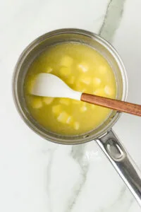 butter melting in a silver pan with a small white and wood handle spatula
