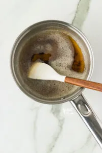 brown butter in a small silver saucepan with a small white spatula with a wood handle