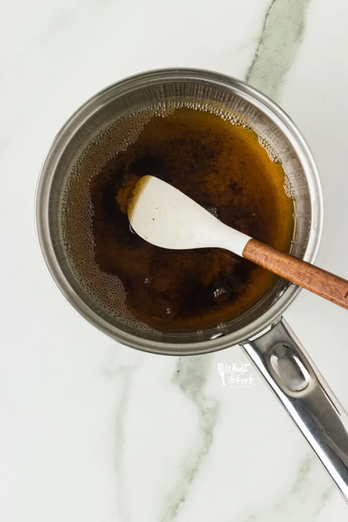 overhead shot of brown butter in a silver pan with a small white and wood handle spatula