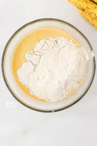 dry ingredients added to the wet ingredients in a clear glass bowl