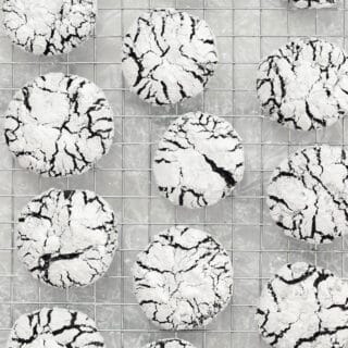 overhead shot of baked Gluten Free Chocolate Crinkle Cookies cooling on a metal wire cooling rack over wax paper