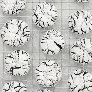 overhead shot of baked Gluten Free Chocolate Crinkle Cookies cooling on a metal wire cooling rack over wax paper