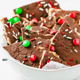 Gluten Free Christmas Cracker Toffee (Christmas Crack) in a white bowl lined with white wax paper
