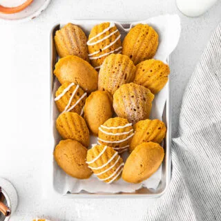 Gluten Free Pumpkin Madeleines arranged on a quarter sheet pan on top of white parchment paper